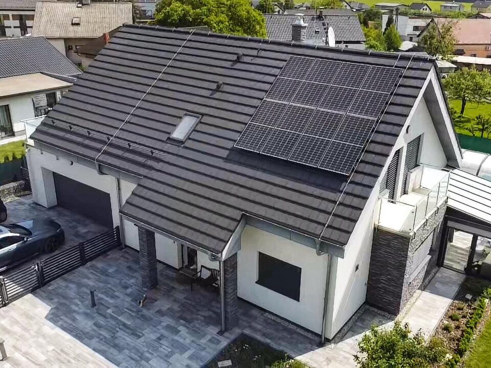 Letecký pohled na dům se solárními panely na střeše.